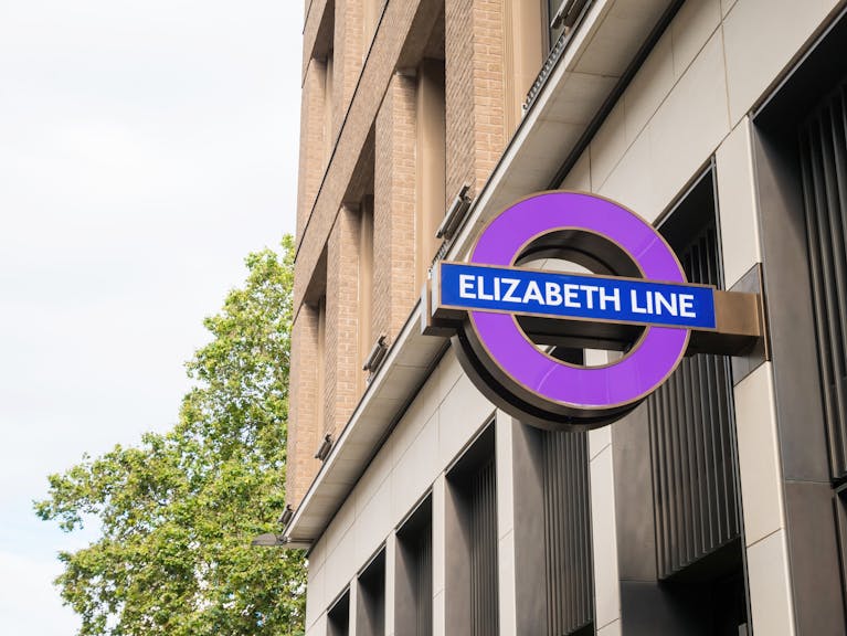 Deep purple Elizabeth Line roundel against crisp building edge