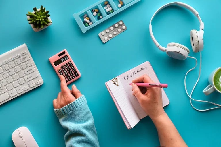 A girl writing in a notebook and using a calculator against a blue background.