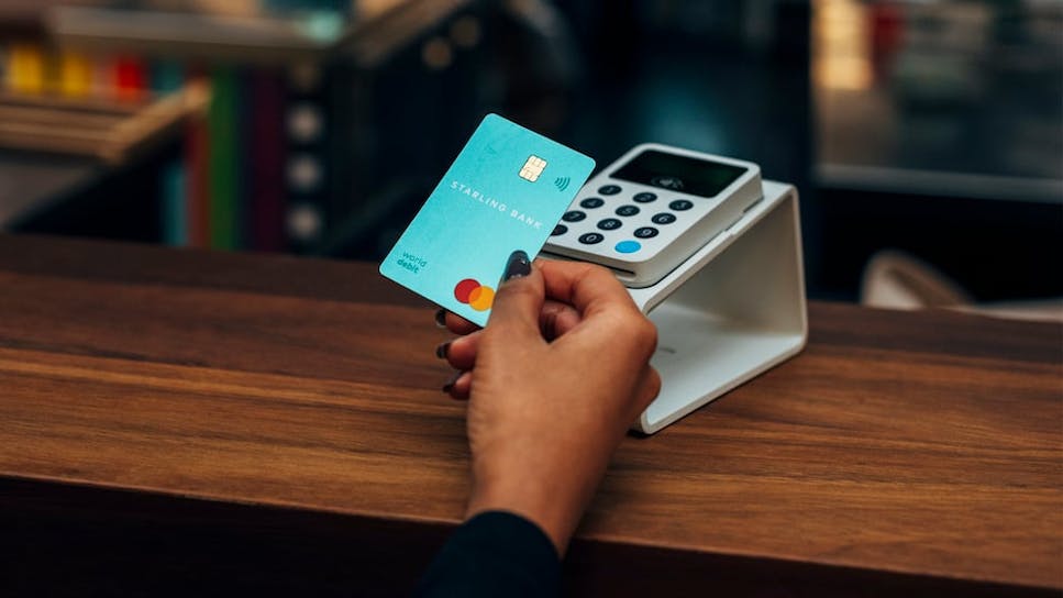 image of person tapping coral blue debit card on card machine