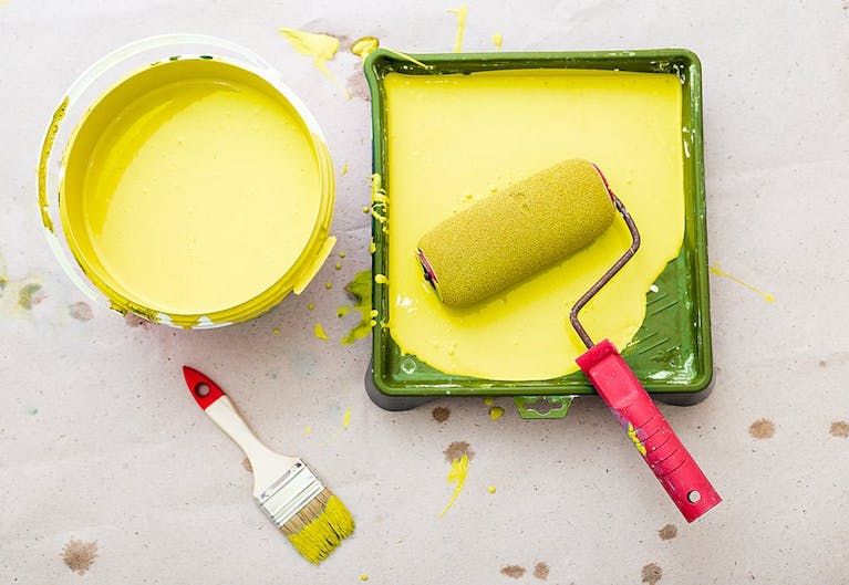 Yellow paint in a can and in a mixing platter, seen from above