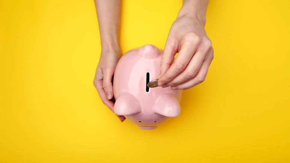 Person putting a coin in a piggybank