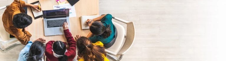 Image shows a group of students chatting around a table