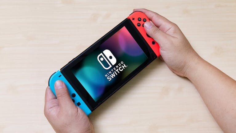 A Nintendo Switch held by a pair of caucasian hands