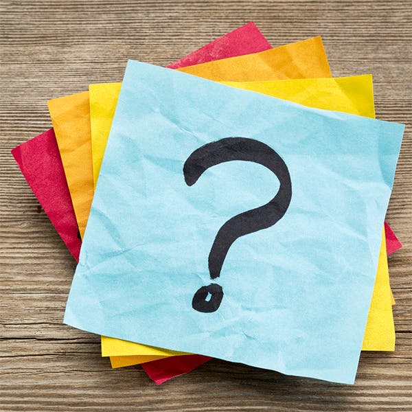A stack of different-coloured Post-It notes with a question mark drawn on the top one.
