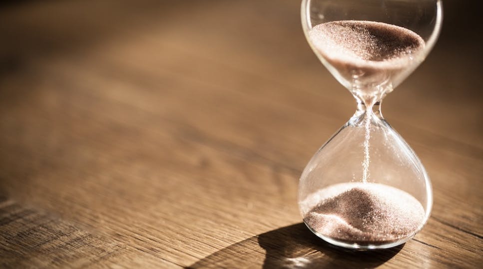 Hourglass filled with golden sand on a wooden table