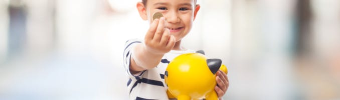 Child putting coins into a piggybank