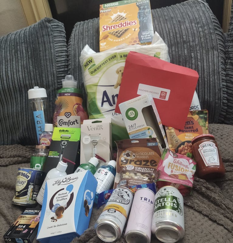 A pile of products including Andrew toilet paper, a box of Shreddies, a can of Stella Artois and a box of chocolates