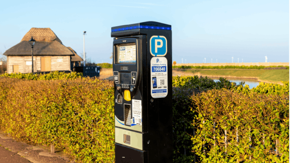Parking meter in a countryside car park with a river behind it.