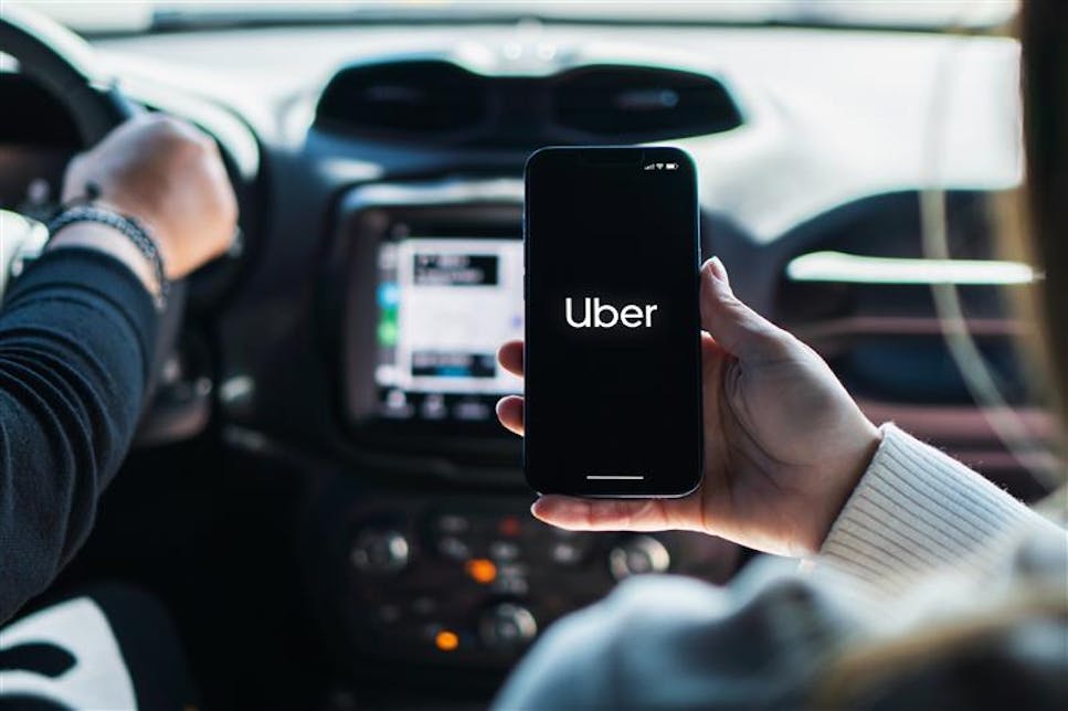 A woman holding her phone with the Uber app open during her ride.