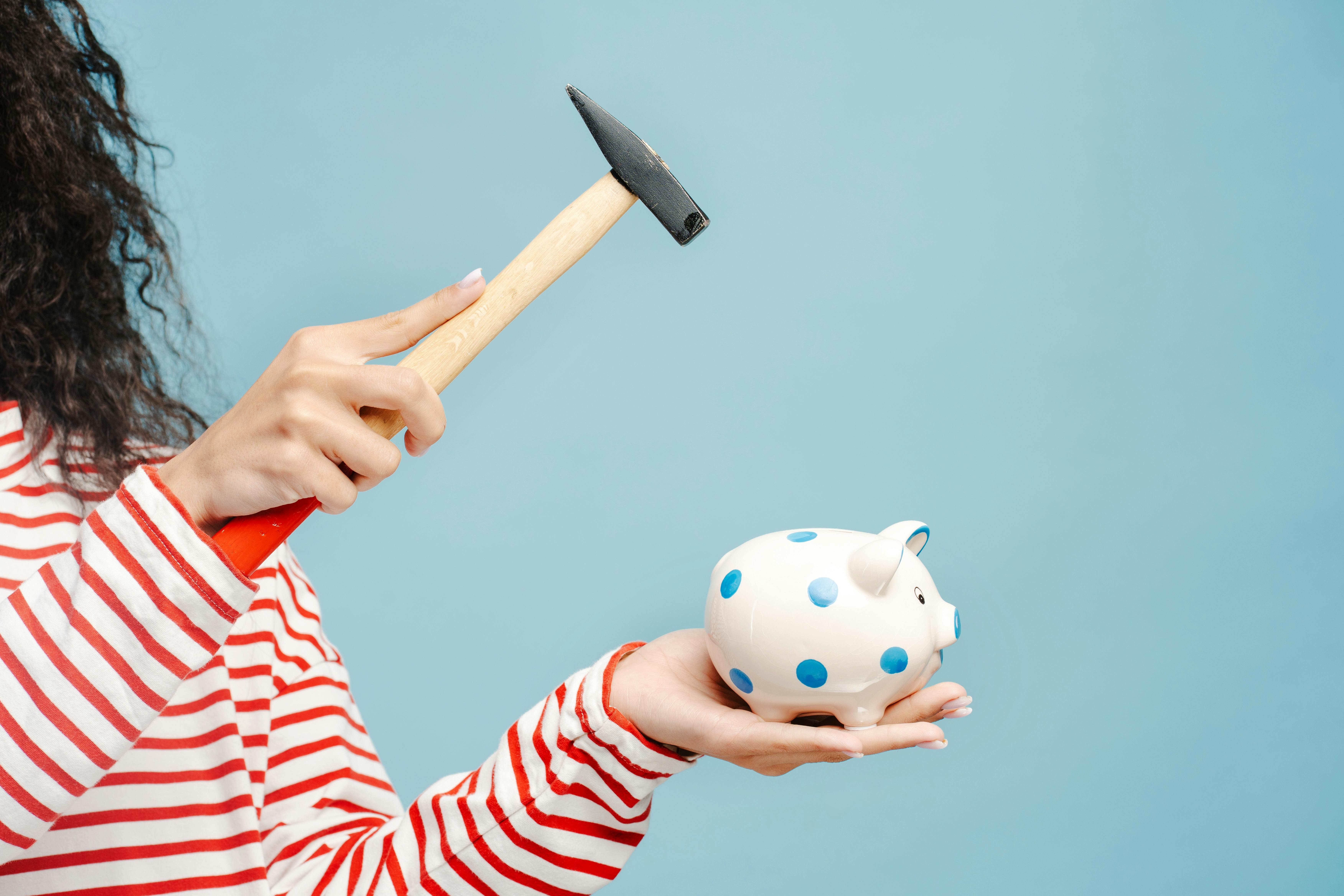 Image showing young woman holding a small hammer and a piggy bank