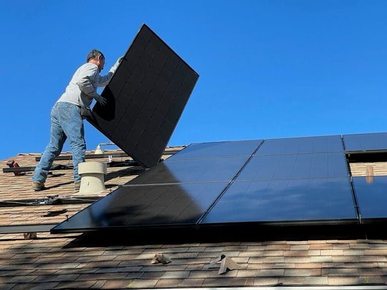 Man installing solar panels on a roof