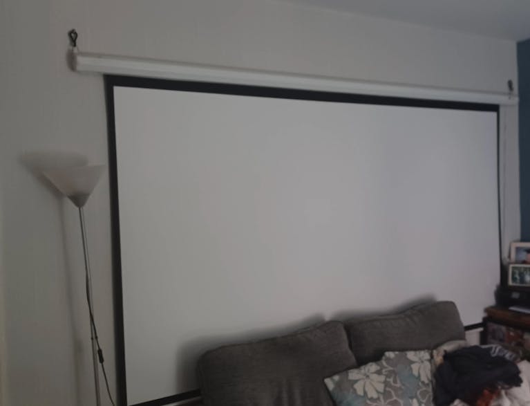 A projector screen against a wall in a dim sitting room