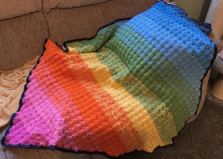 A crochet blanket in rainbow colour stripes