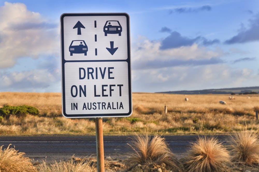 A road sign reading "Drive on left in Australia".