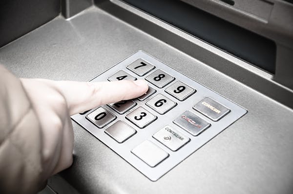 A person entering their PIN at a cash machine.