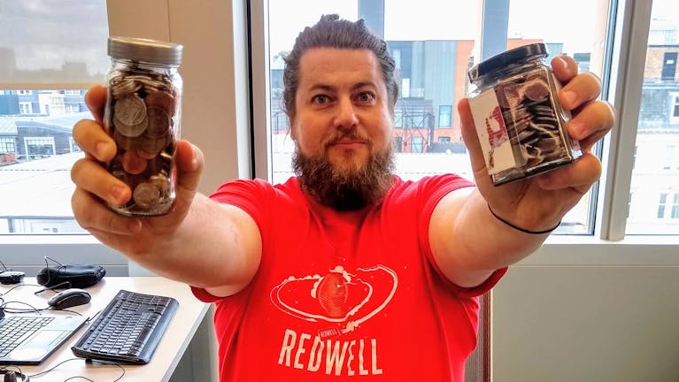 The MoneySavingIdiot holding up a jar of coins in each hand.
