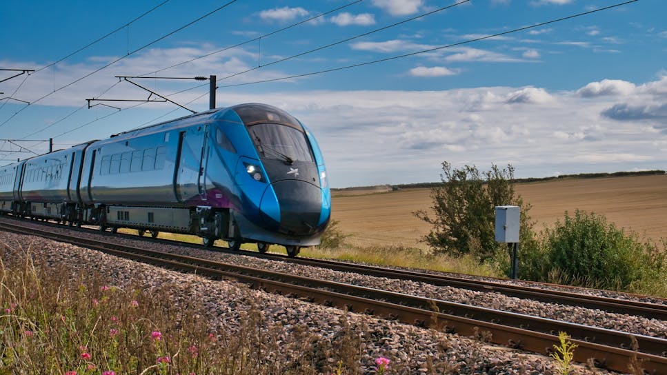 Blue train travelling at speed in Northumberland, taken on a sunny day with white clouds