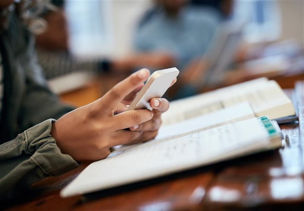 Image shows a young person's hands holding a mobile phone